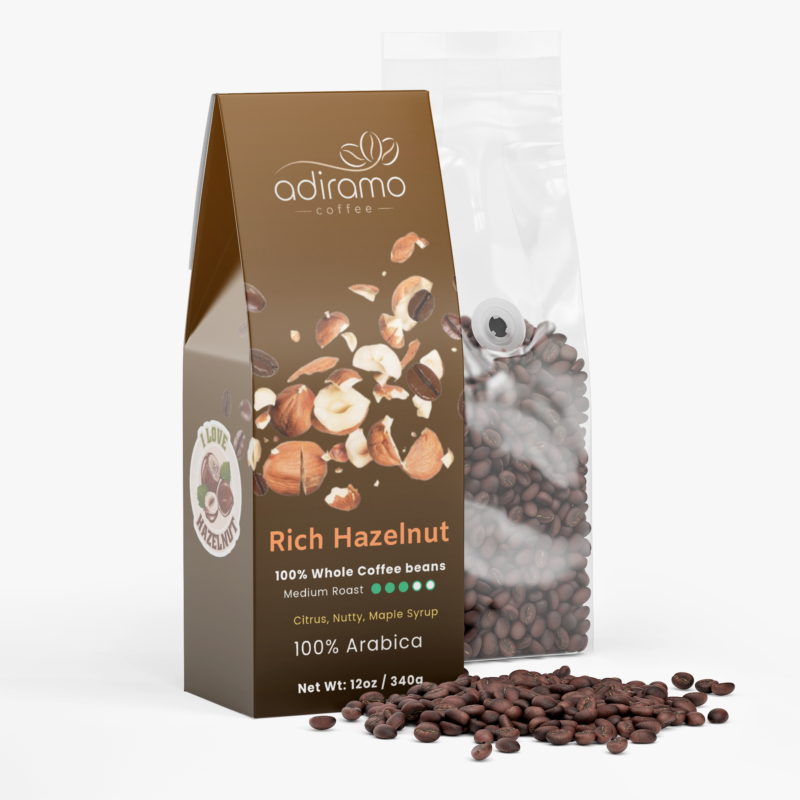 Adiramo Rich Hazelnut 12oz medium roast coffee retail box featuring flying hazelnut graphics standing beside a clear valve bag of whole coffee beans